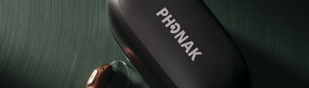 Phonak hearing aid next to its charging case