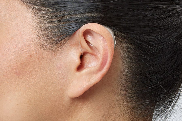 Woman wearing an Oticon miniRITE R hearing aid in Chroma Beige – close-up at a 90 degree angle