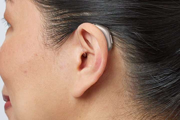 Woman wearing an Oticon miniRITE R hearing aid in Chroma Beige – close-up at a 45 degree angle